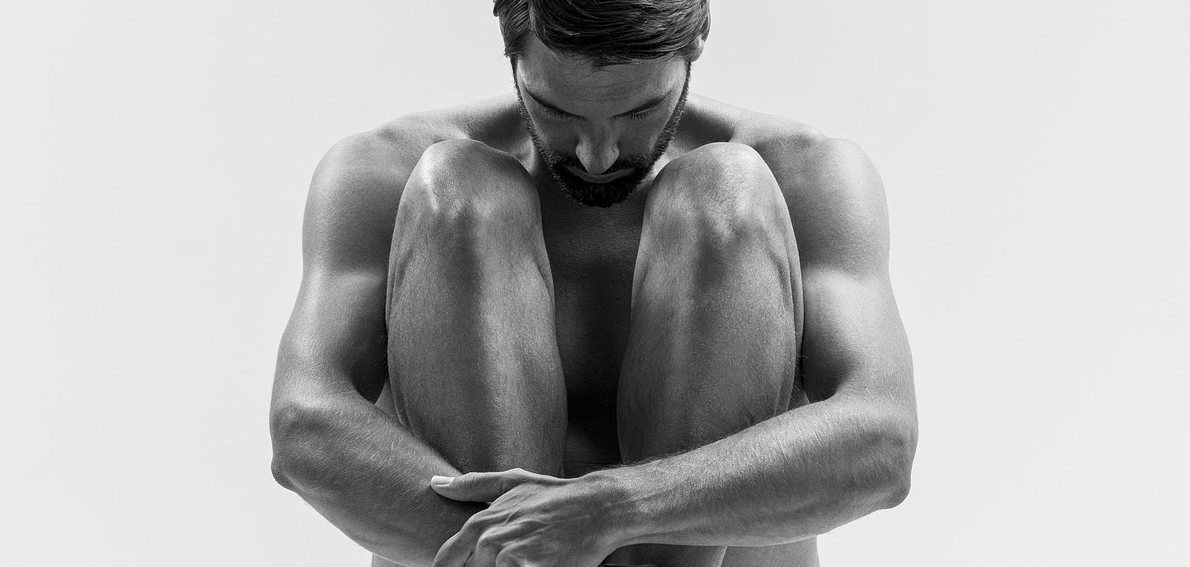 Black and white photo of crouching muscular man, wellness concept
