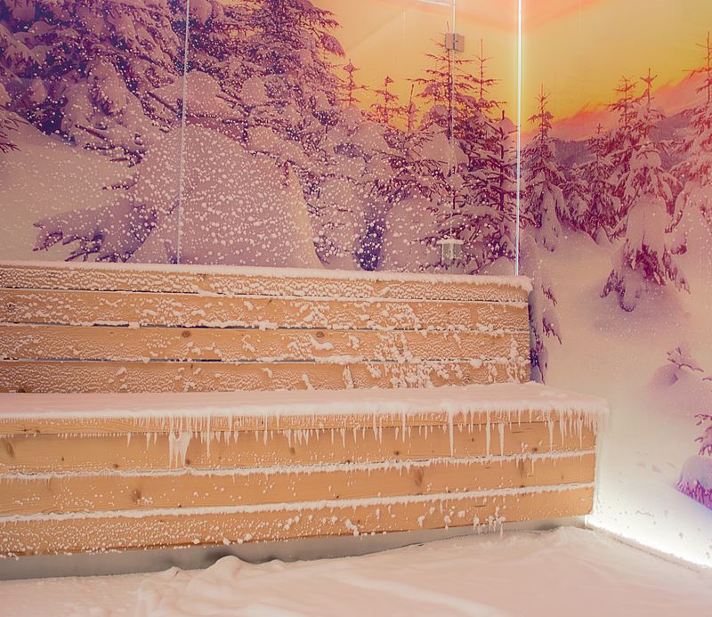 Schneeraum mit Holzbank, Pulverschnee und warm beleuchteter Winterlandschafts-Wandgrafik.