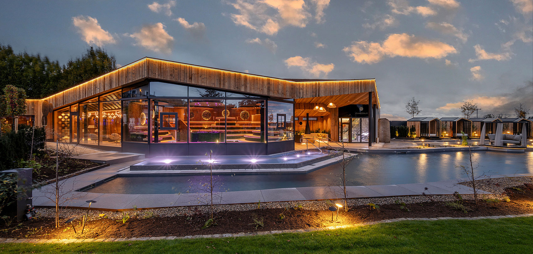 Großzügige Spa-Anlage mit Glasfassade, Pool und Lichtinstallation im Abendlicht