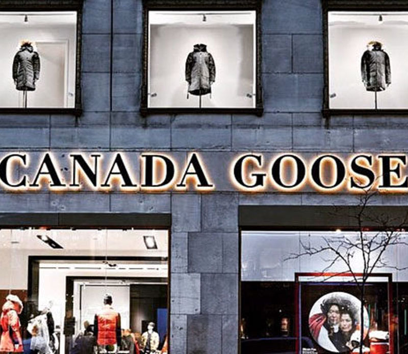 Canada Goose Flagship Store Fassade mit beleuchtetem Logo und Jacken in Schaufenstern.
