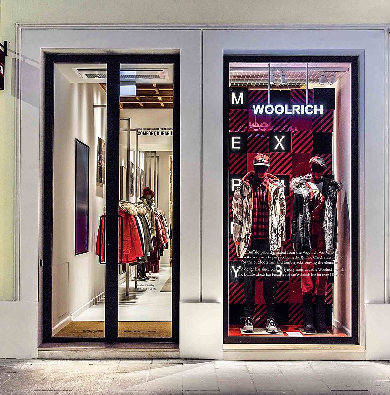 Woolrich storefront at night with illuminated display window and Buffalo Check display