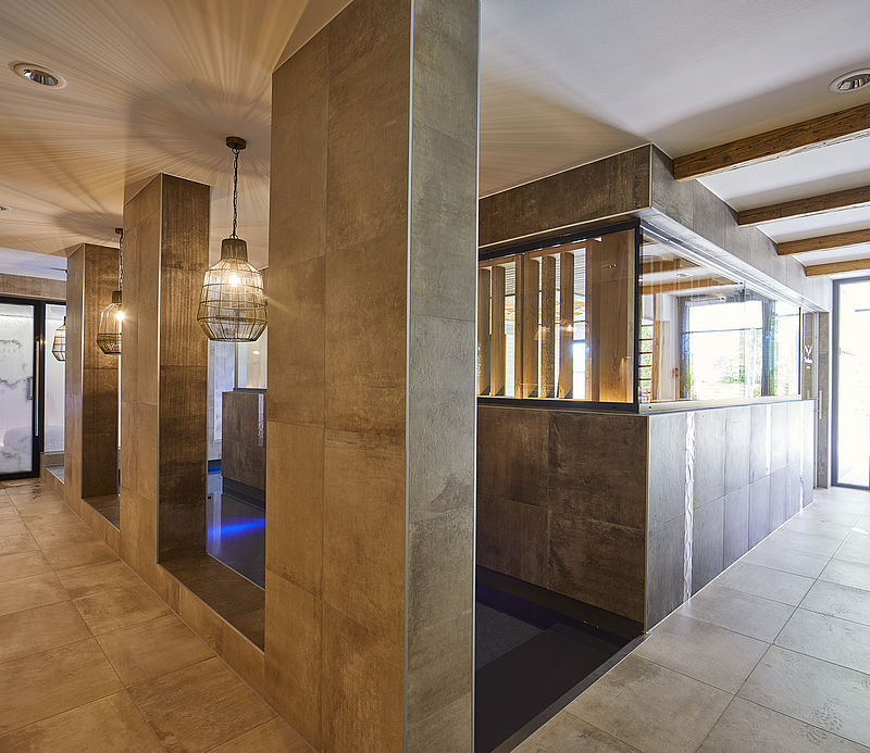 Modern wellness anteroom with stone walls, wooden ceiling and pendant lights.