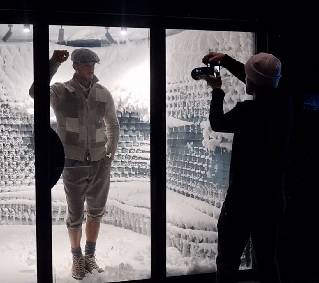 Photographe filme modèle dans vitrine avec parois givrées et neige
