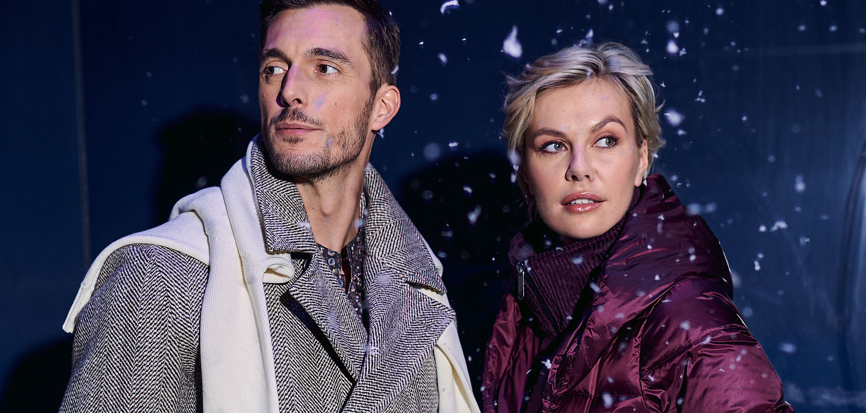 Homme et femme en mode hivernal avec manteau et doudoune devant décor enneigé avec flocons