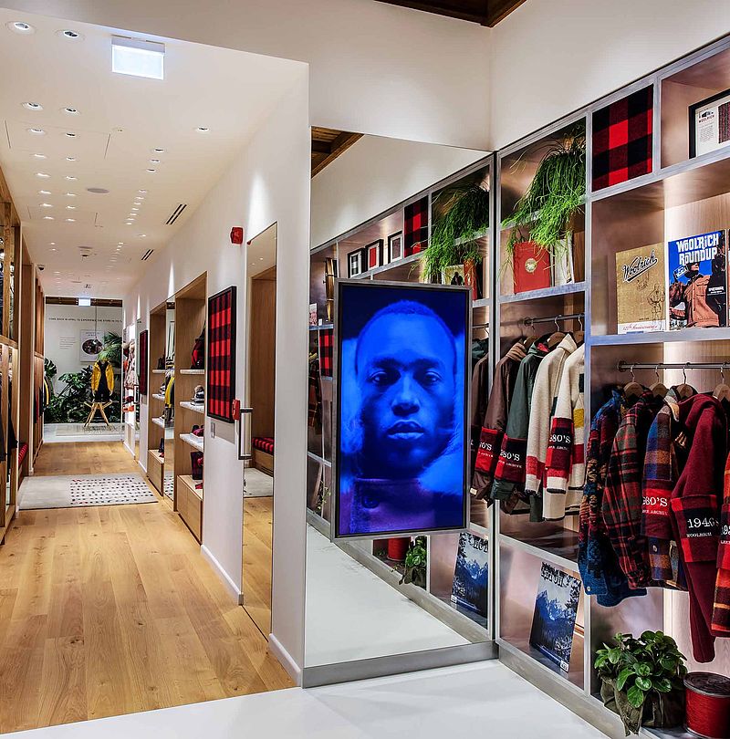 Woolrich store corridor with vintage wool sweaters, archive exhibits and digital portrait screen