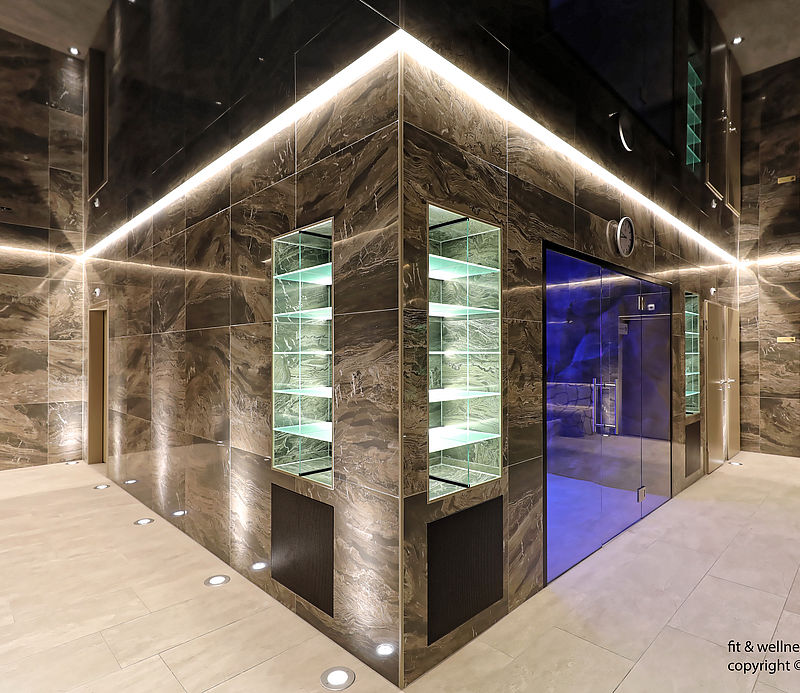 Elegant spa area with marble walls, LED lighting and glass door to blue-lit snow cabin.