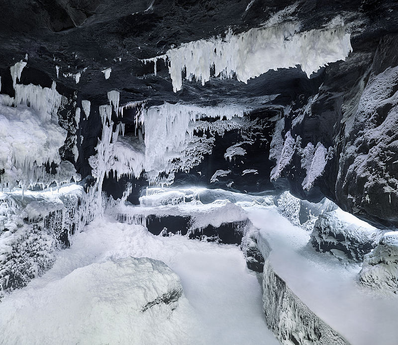 Impressive ice and snow formations in dark snow grotto with natural cave aesthetic.