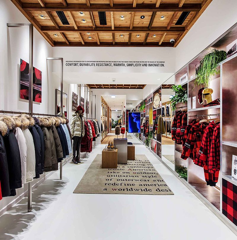 Woolrich store corridor with red plaid shirts, parka rows and wooden beam ceiling
