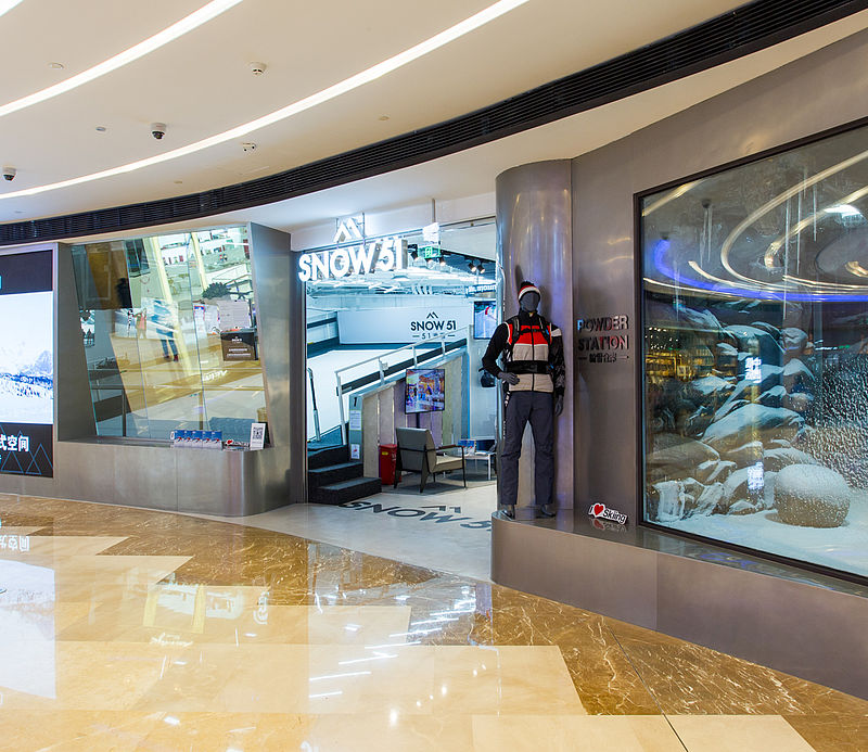 Entrance of SNOW51 Concept Store in shopping center with display window and snow chamber view.