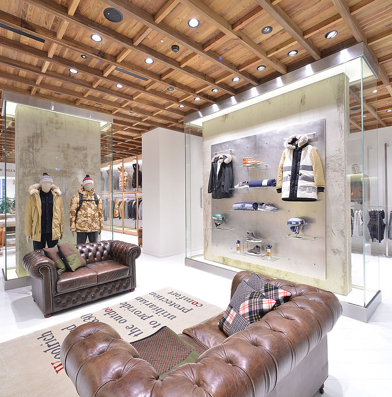 Woolrich flagship store interior with wooden ceiling, Chesterfield sofas and mannequins in winter jackets